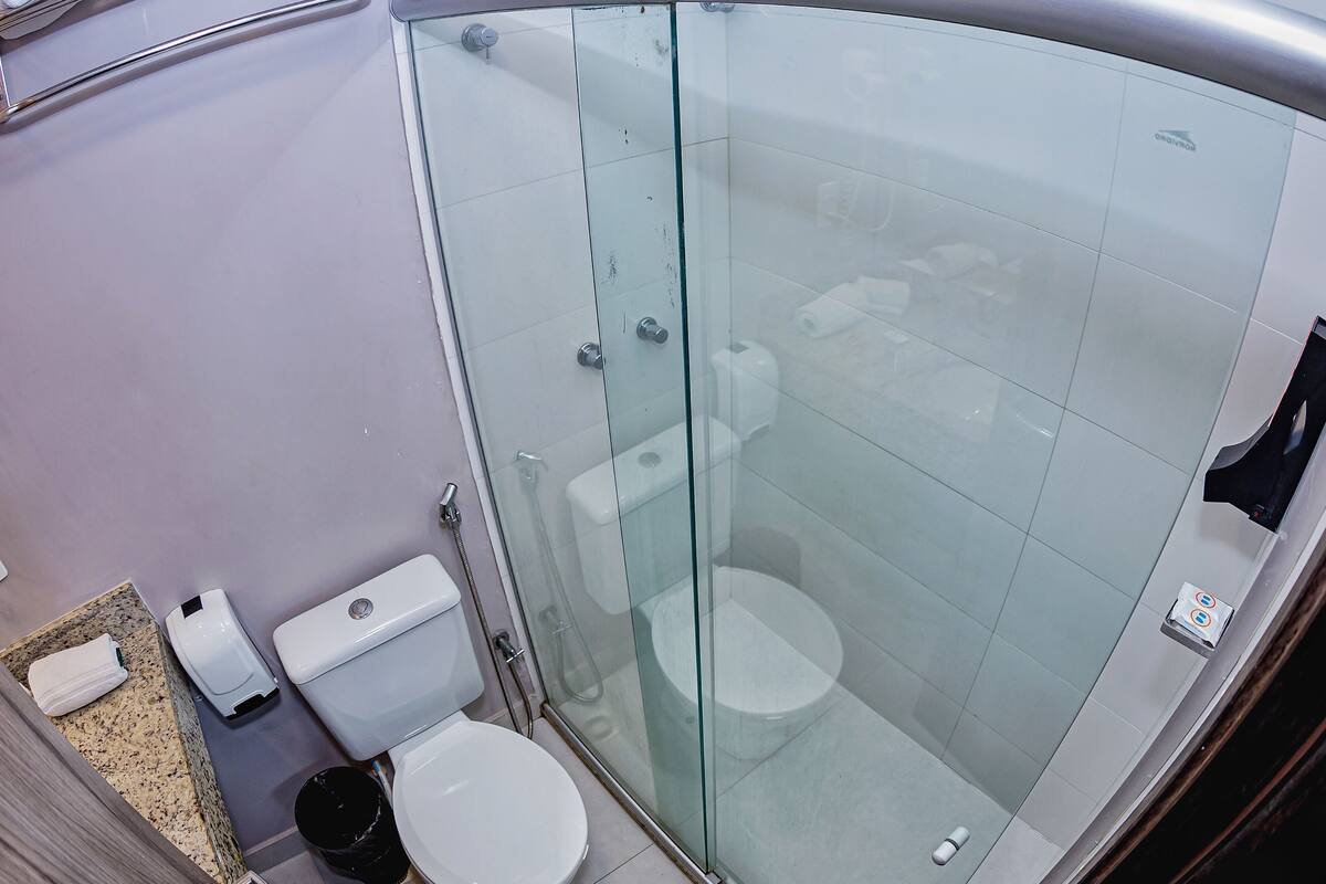 A modern bathroom with a glass-enclosed shower, a toilet, and a sink.