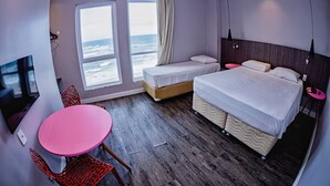 A hotel room with a bed, a small table, and chairs. There are two windows with ocean views. - B Hotel (Salvador)
