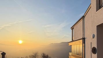 Ein Gebäude mit modernem Design, einem gepflasterten Innenhof und Blick auf einen Hügellandstrum gegen den Sonnenuntergang.