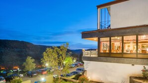 A modern hotel with a dining area, a parking lot, and a view of the surrounding hills. - Waldhotel Sonnenberg (Bollendorf)