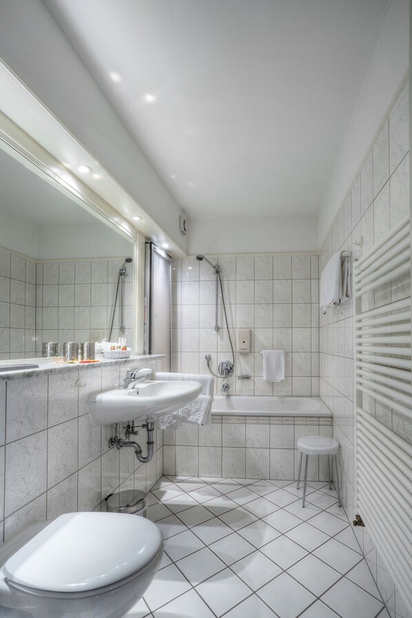 A modern bathroom with a toilet, sink, and bathtub. - Waldhotel Sonnenberg (Bollendorf)