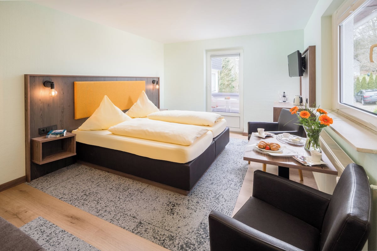 Una habitación de hotel moderna con cama, mesita de noche, silla y ventana con vistas.