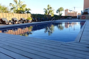 Una piscina con sillas de descanso y una terraza de madera.
