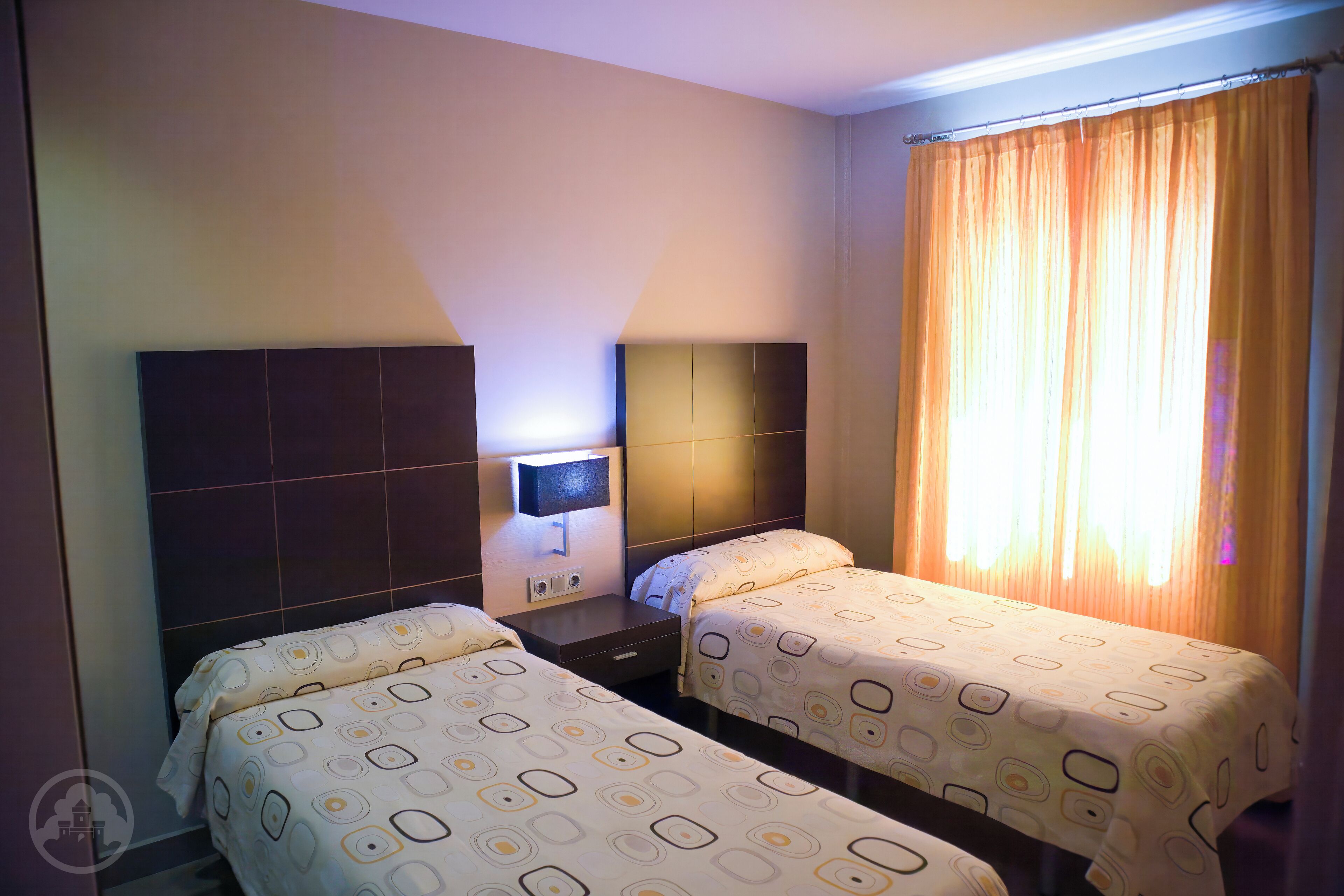 A hotel room with two beds, a TV, and a window with curtains.