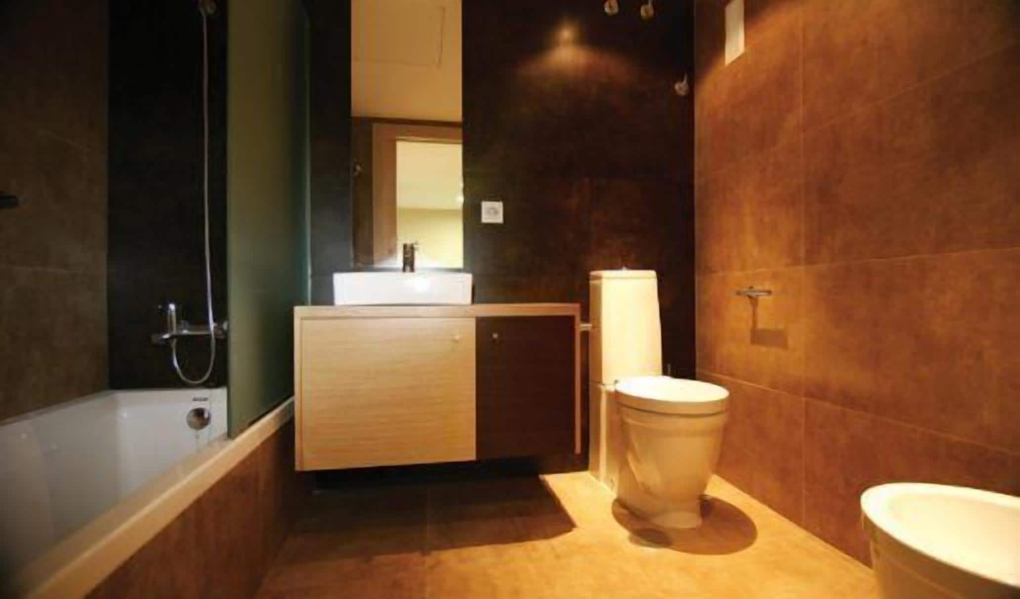 A modern bathroom with a bathtub, a toilet, and a sink.