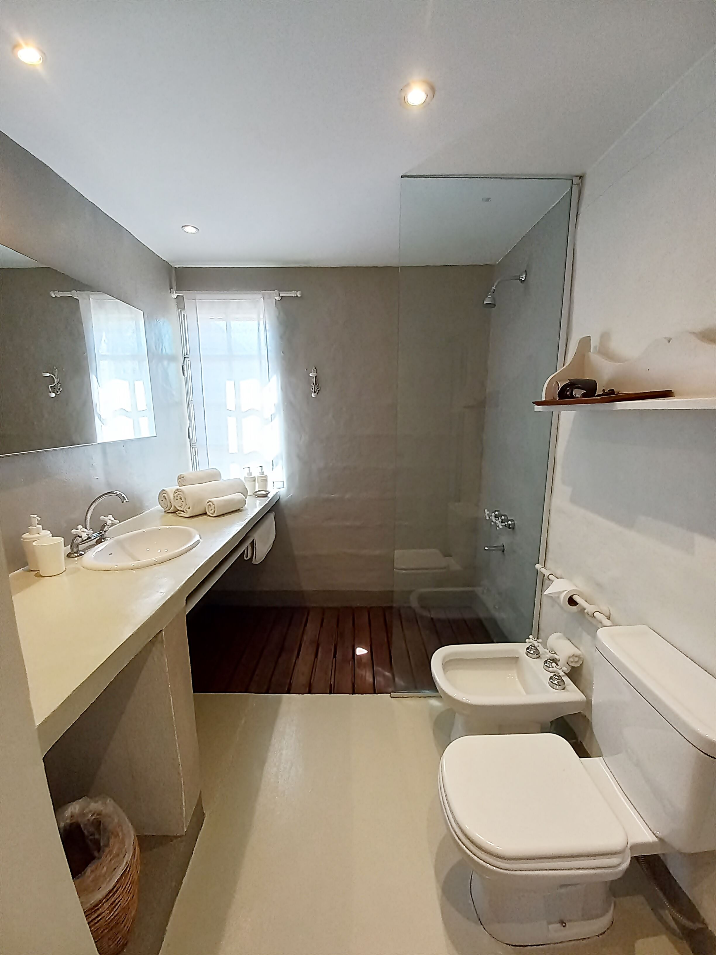 A modern bathroom with a large mirror, a sink, a toilet, and a shower area.