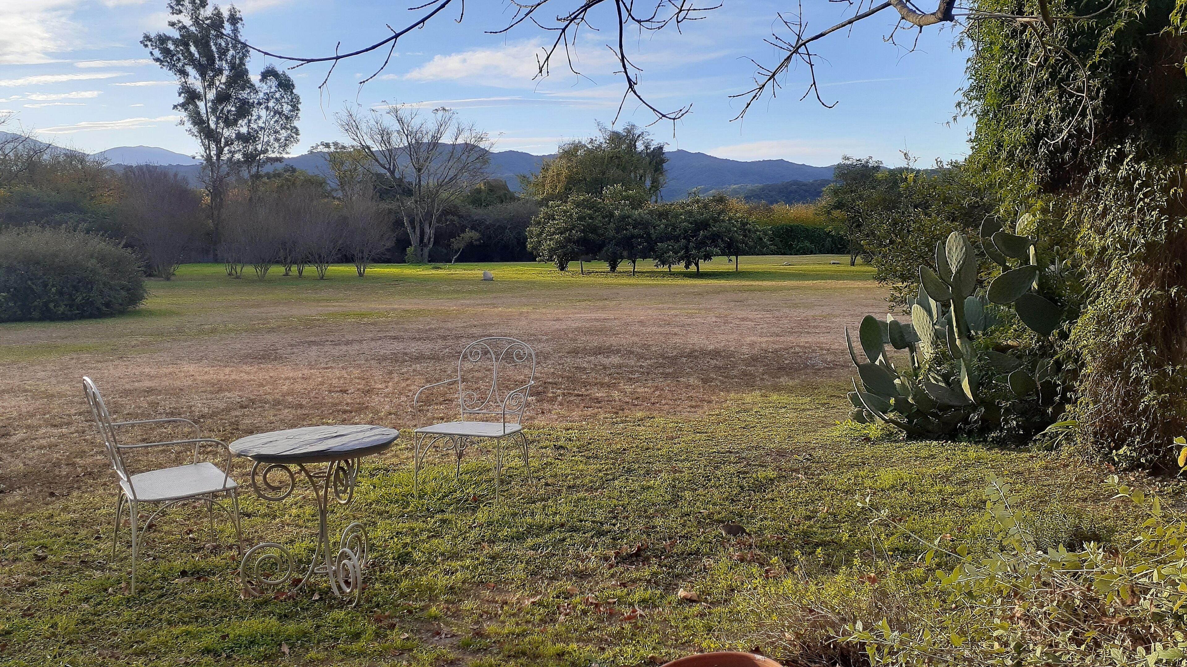A grassy outdoor area with a metal table and two chairs.