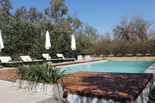 Una piscina al aire libre, sombrillas, tumbonas