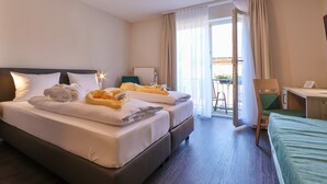 Een hotelkamer met een groot bed, een bureau en een stoel. Er is een raam met gordijnen en uitzicht op de omgeving.