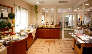 Een buffetopstelling met diverse gerechten en een keuken op de achtergrond.