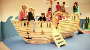 Een speelgebied met een houten schip speeltuinconstructie.