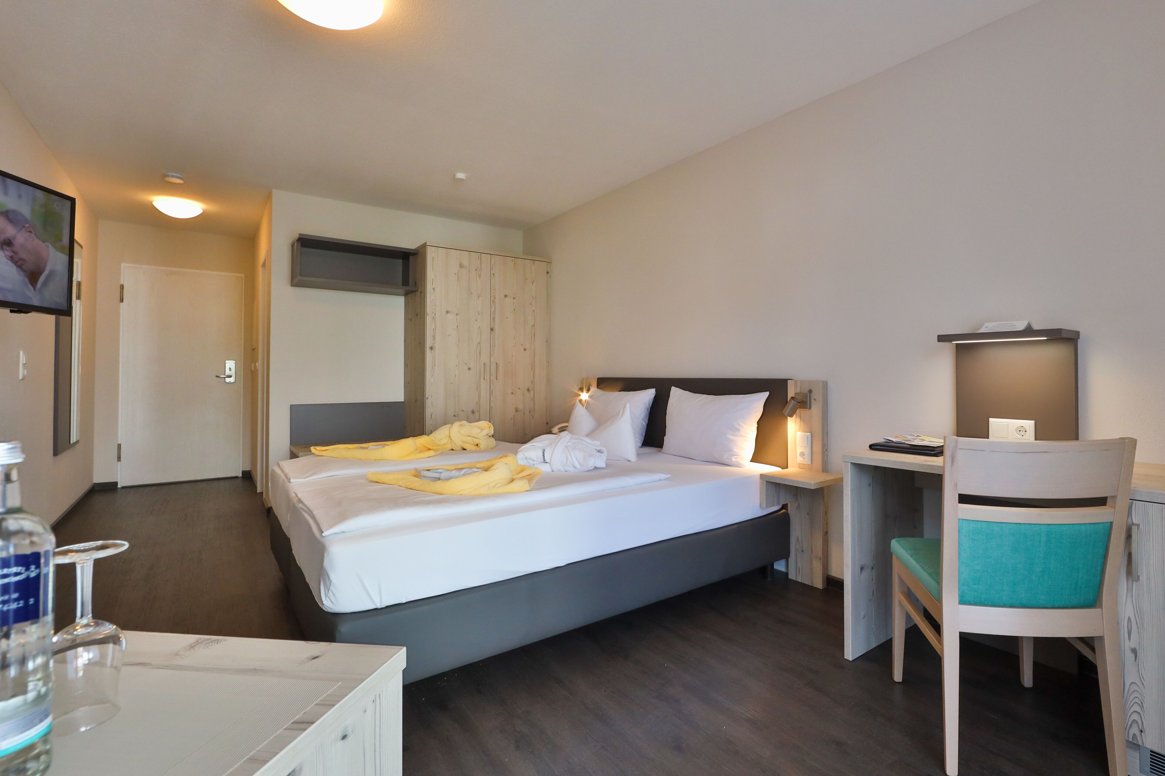 Una habitación de hotel con cama, mesita de noche, silla, escritorio y televisor.