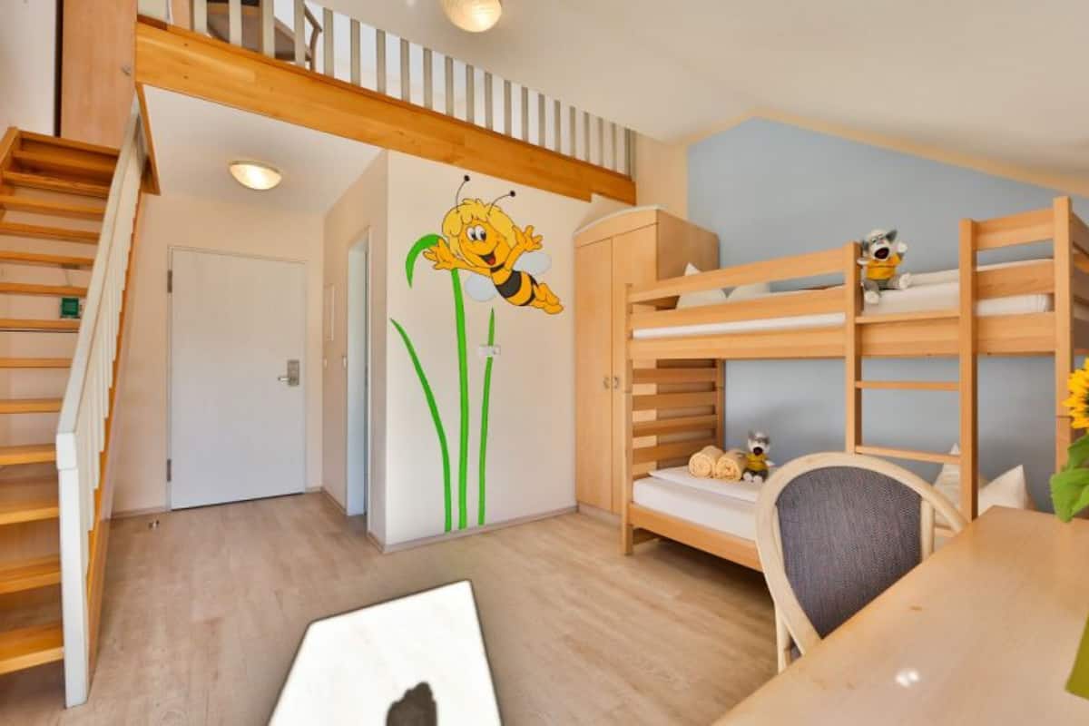 Ein Kinderzimmer mit Etagenbetten, einem Schreibtisch und einem Stuhl.