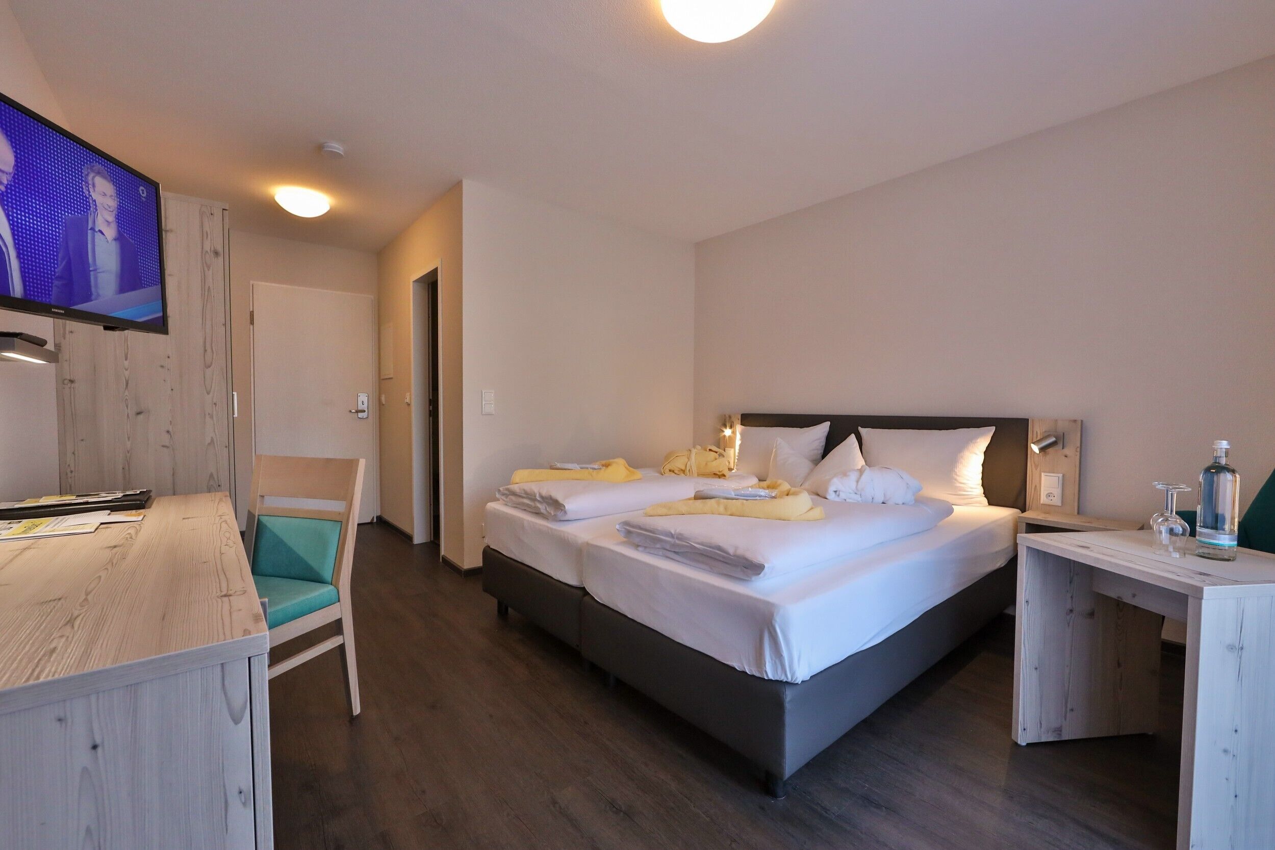 A hotel room with a bed, a desk, a chair, and a television.