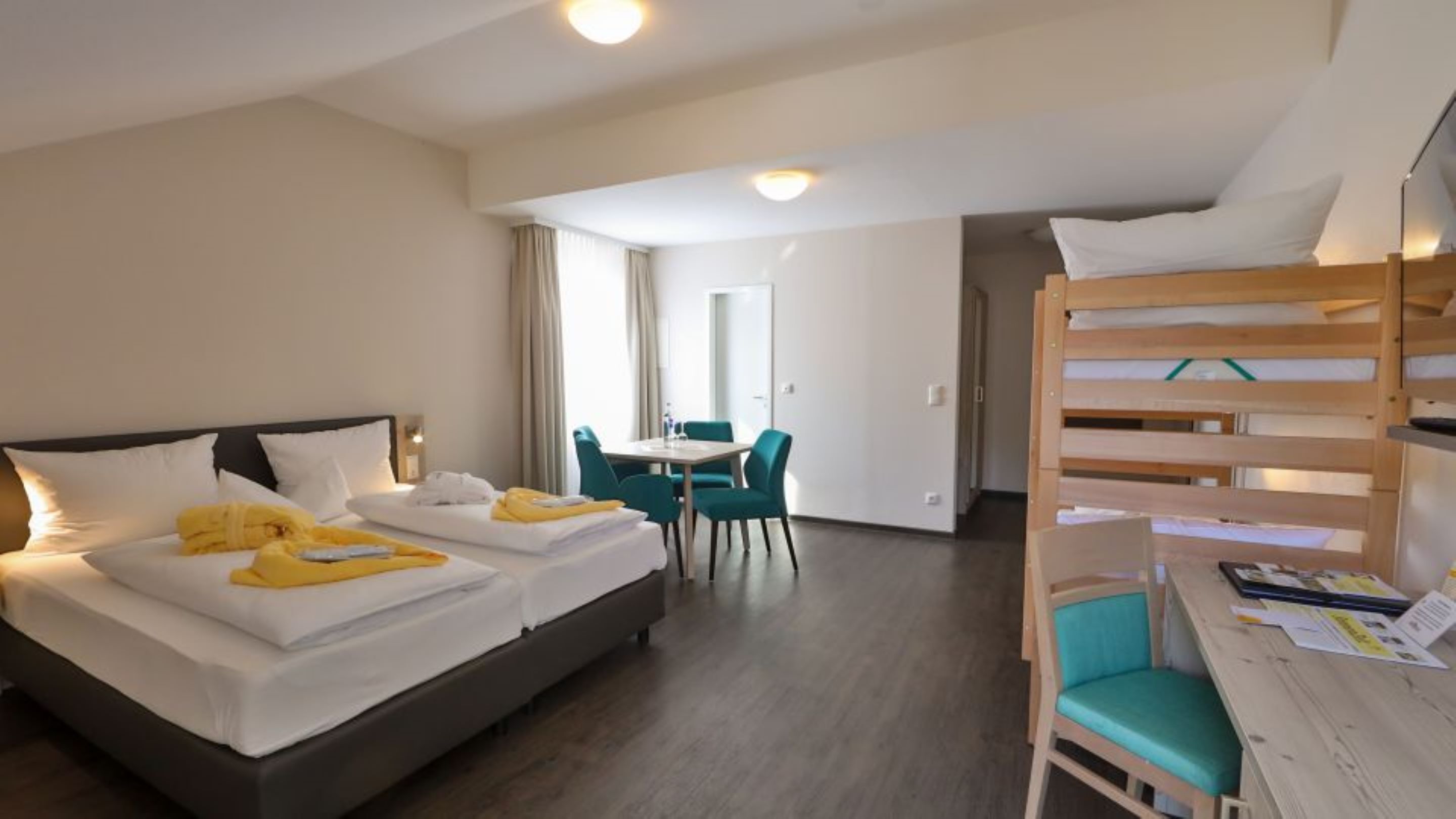 Una habitación de hotel con dos camas, un escritorio y una litera.