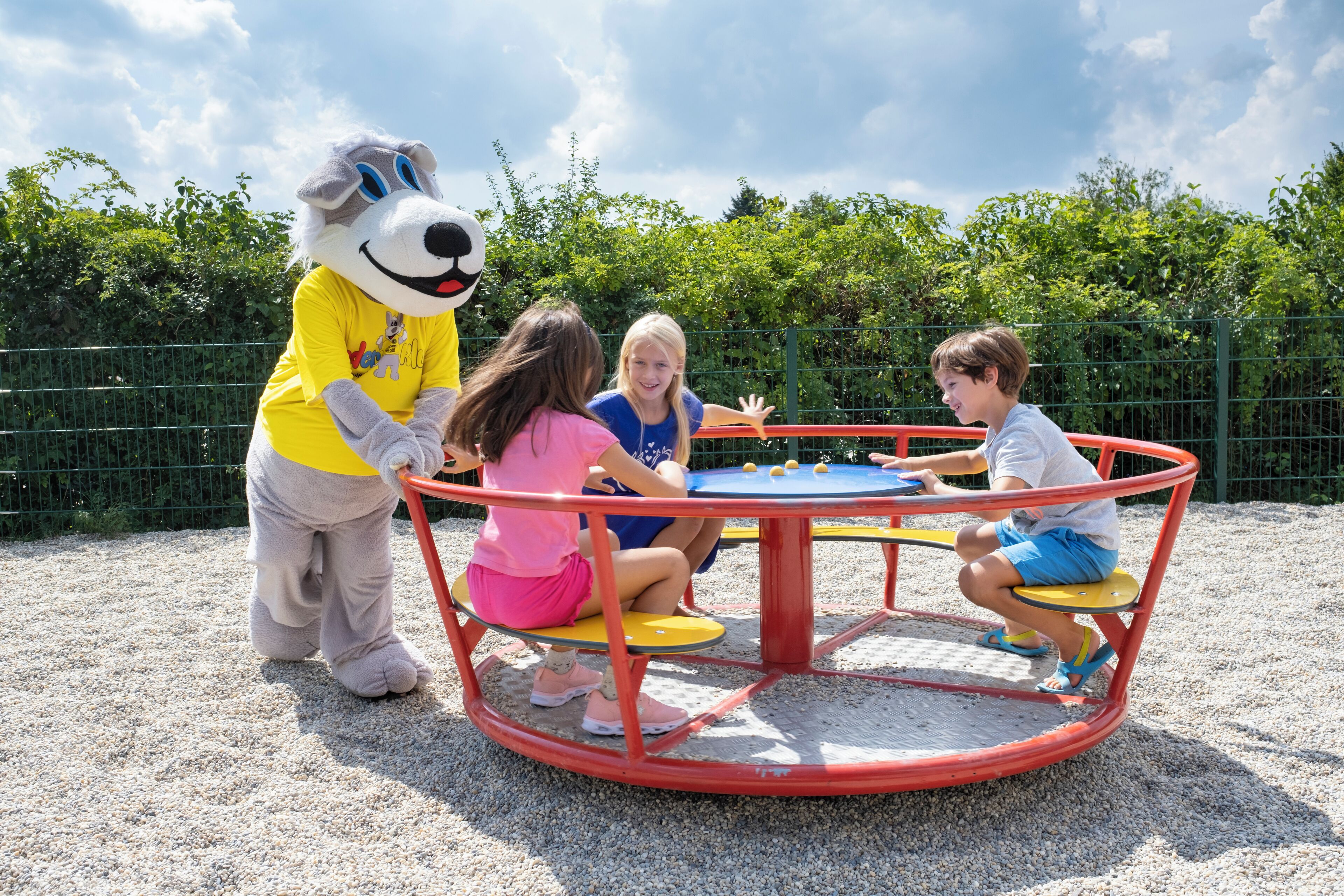 Un personatge publicitari interactua amb nens en un parc infantil.