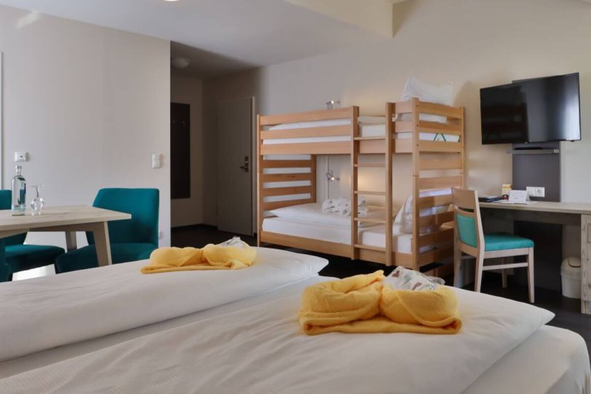 Ein Hotelzimmer mit zwei Betten, einem Schreibtisch, einem Fernseher und einem Badezimmer.