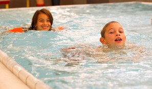 Twee kinderen in een zwembad met helder water.