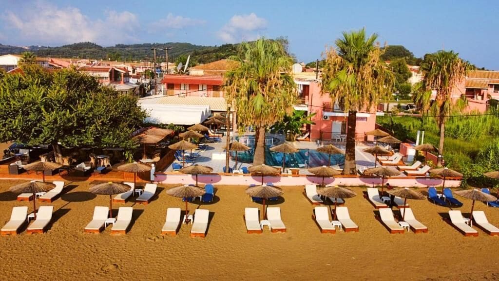 Un complejo turístico en la playa con tumbonas, sombrillas y una zona de piscina.