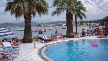Una piscina al aire libre, sombrillas, sillones reclinables de piscina