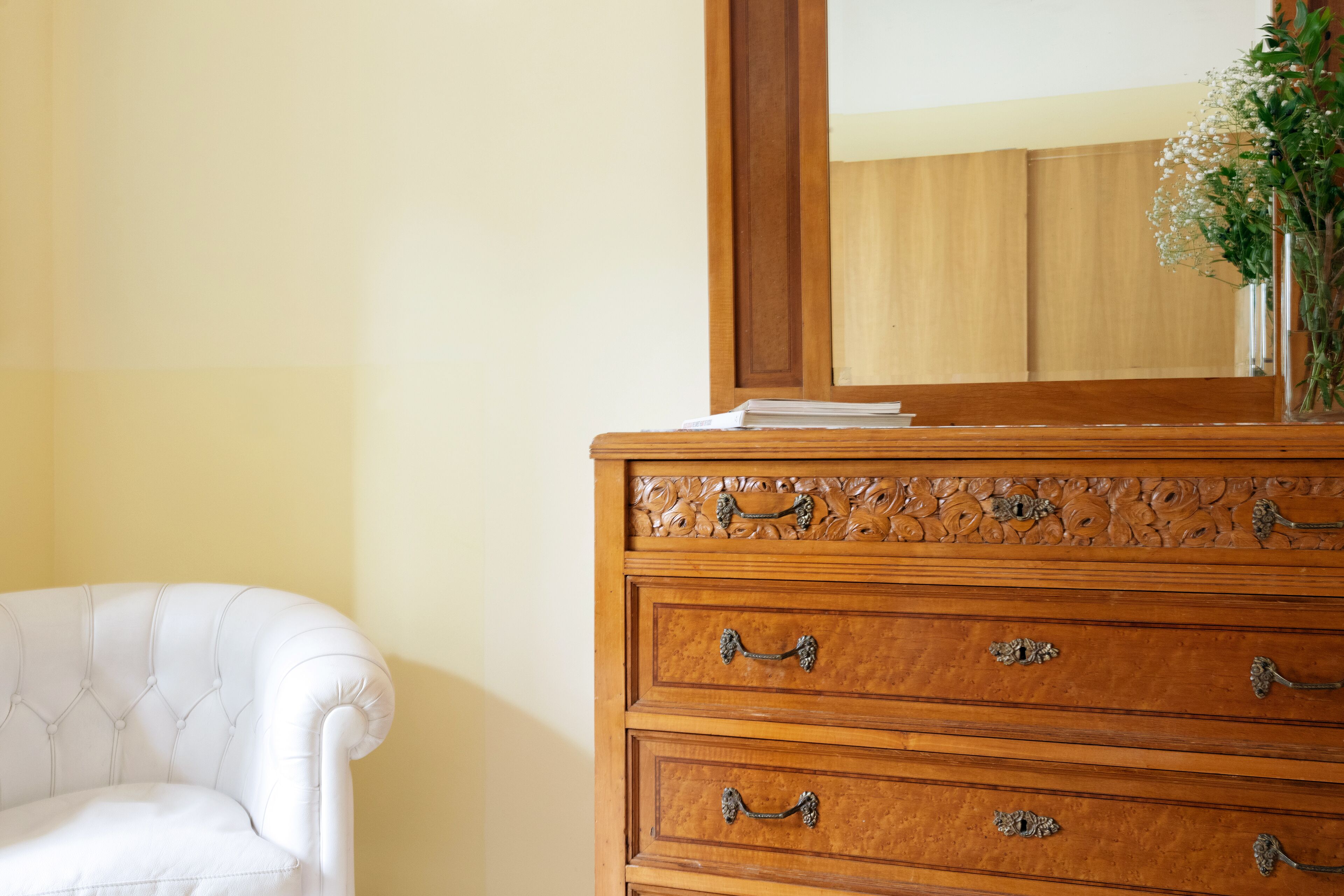 Un comò in legno con maniglie elaborate e uno specchio sopra.