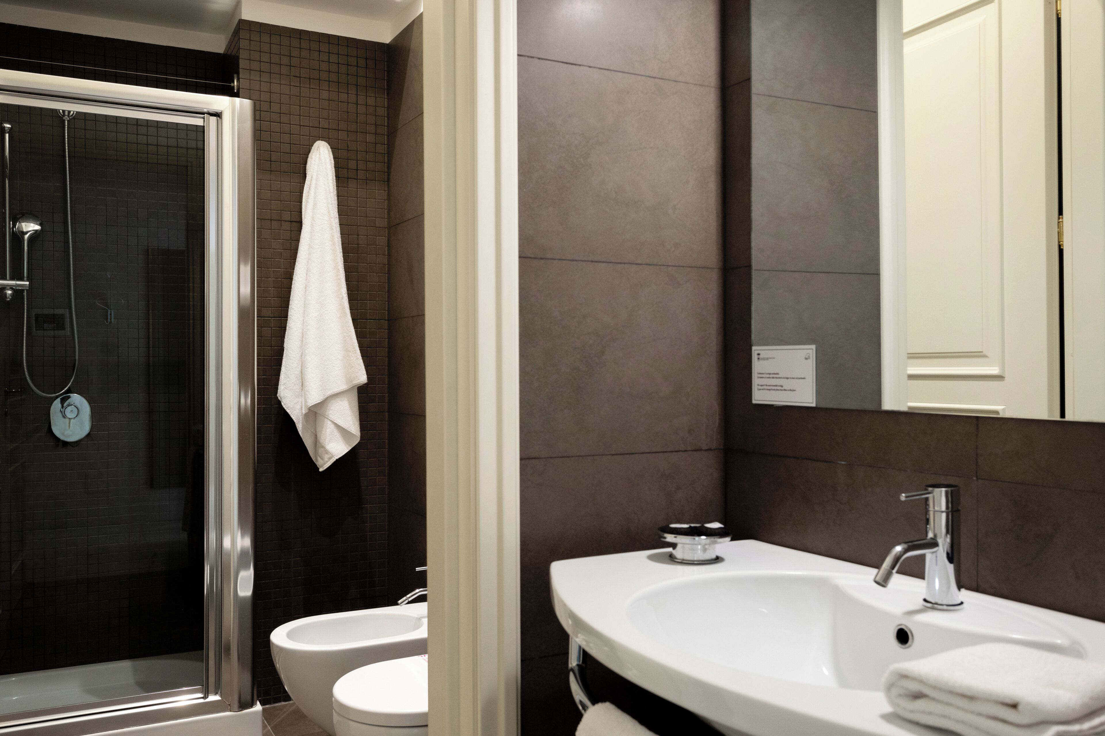 A modern bathroom with a glass-enclosed shower, two sinks, and a large mirror.