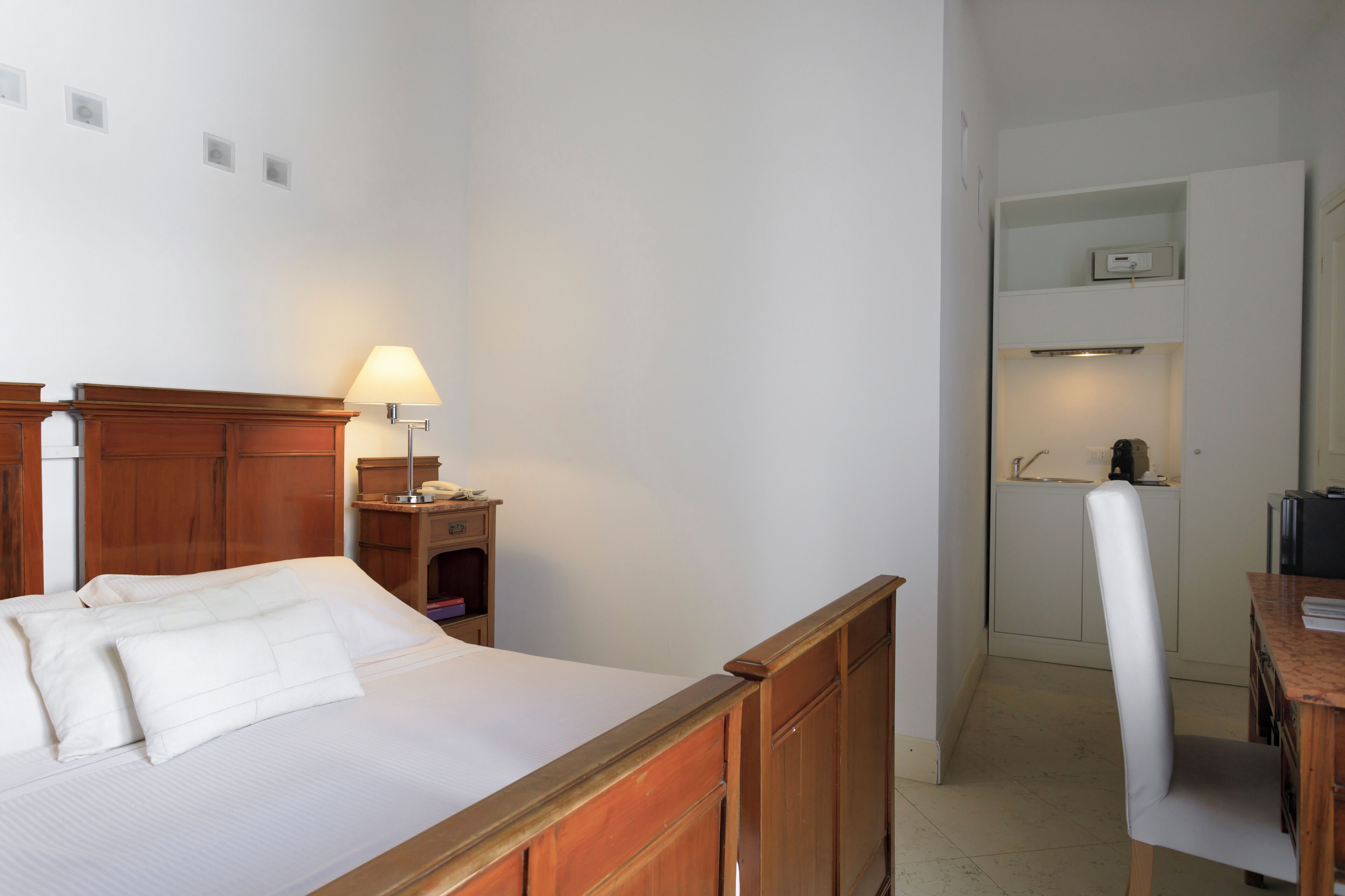 Une chambre à coucher avec un lit en bois, une table de chevet avec une lampe et un petit bureau avec une chaise.