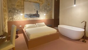 A bedroom with a large bed, a bathtub, and a stone wall with a painting. - Palazzo Brunaccini Boutique Hotel (Palermo)