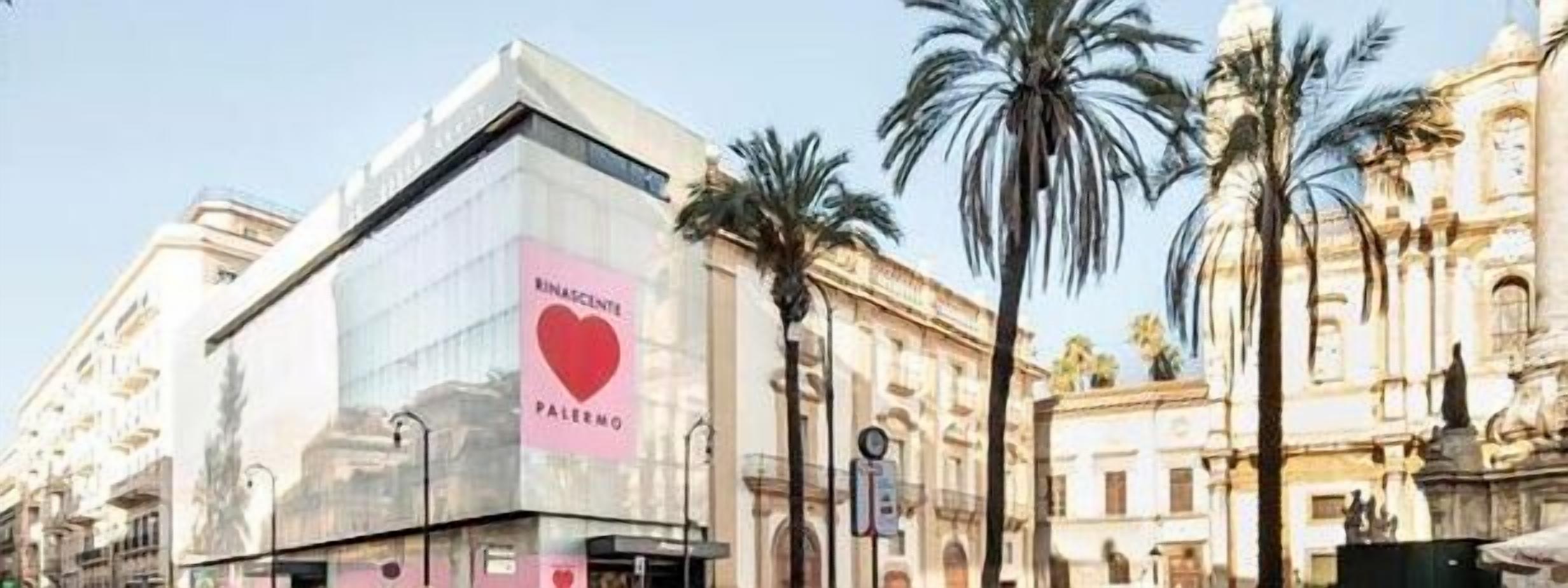 Um edifício moderno com um grande letreiro em formato de coração com a inscrição 'RINASCENTE PALERMO'.