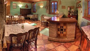A rustic dining area with wooden furniture, a tiled floor, and a bar area with a checkered pattern. - Bodegas de Arnés - Adults Only (Graus)