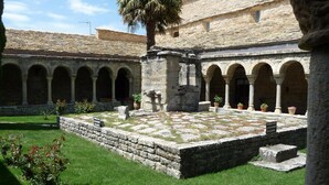 A courtyard with stone arches, a palm tree, and potted plants. - Bodegas de Arnés - Adults Only (Graus)