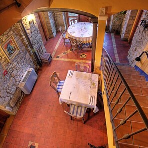 A dining area with a stone wall, a table set for two, and a staircase leading to an upper level. - Bodegas de Arnés - Adults Only (Graus)