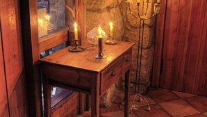 A wooden desk with a mirror, a candelabra with lit candles, and a stone wall. - Bodegas de Arnés - Adults Only (Graus)