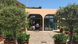 A building entrance with a paved pathway leading to it, surrounded by potted plants. - Hotel Riviera Lido (Milazzo)