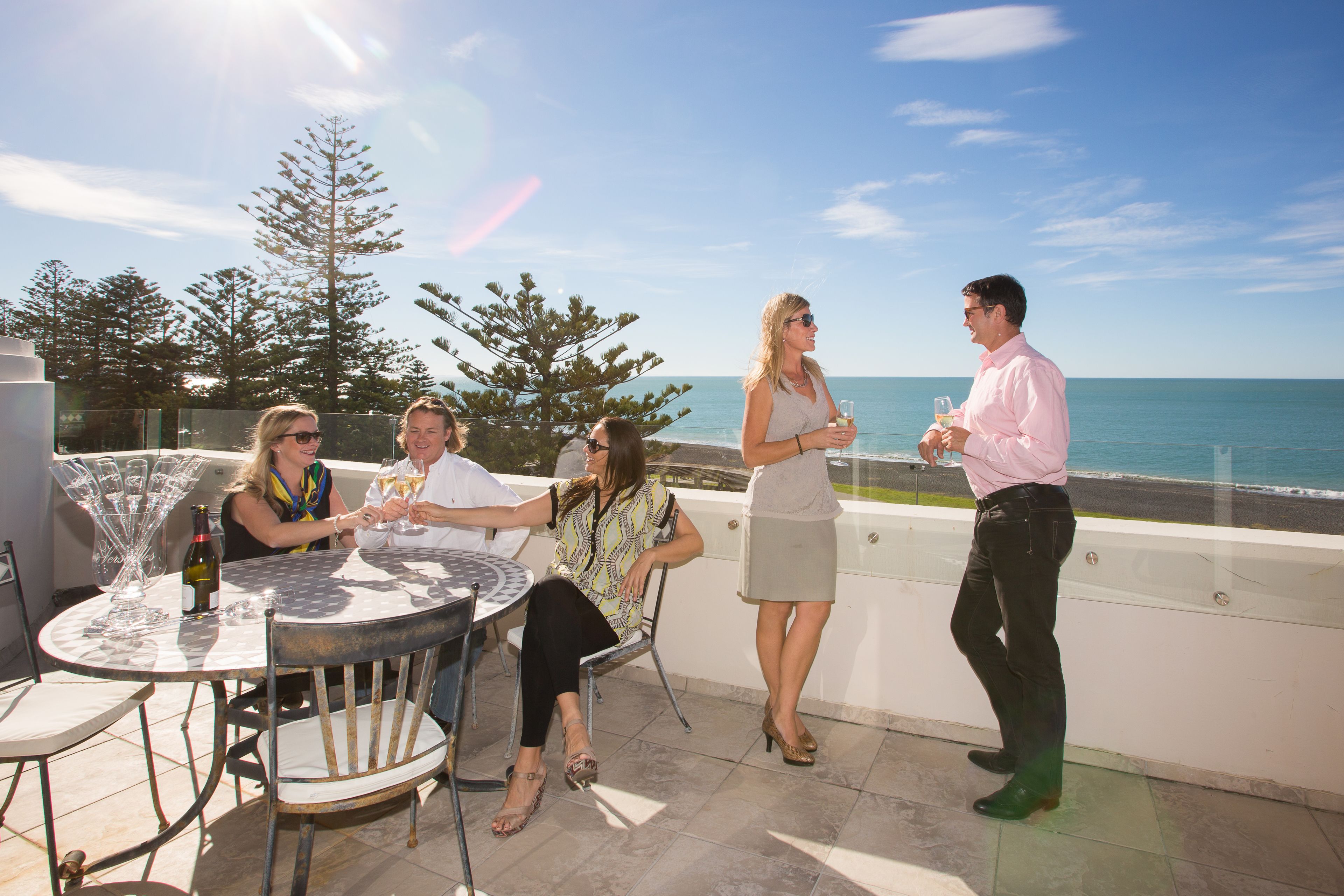 A group of people at an outdoor patio with a view of the ocean.