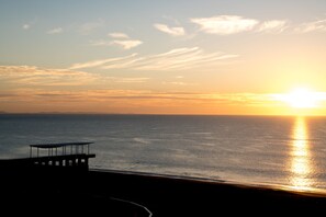 Une vue sur le coucher de soleil depuis une jetée, avec un banc, donnant sur l’océan.