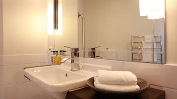 A modern bathroom with a white sink, a mirror, and a towel rack.
