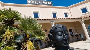 Um hotel chamado "Hôtel Ya'Tis" com uma estátua de Buda em frente.