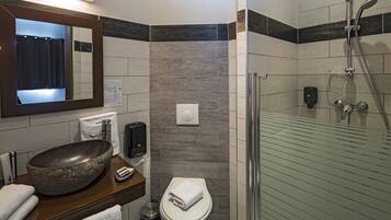 Une salle de bain moderne avec un grand lavabo sur pied, des toilettes, une douche en verre et un miroir au-dessus du lavabo.