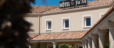 Un hotel con un letrero que dice "Hôtel Ya'Tis" y un techo de tejas.