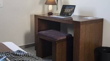 Ein kleiner Holztisch mit einem Laptop, einer Lampe und einer Vase.