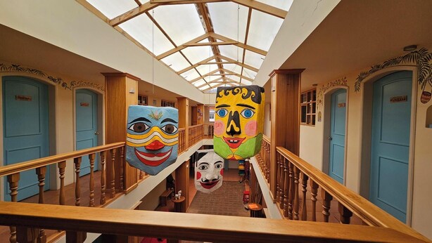 A hotel corridor with a skylight, wooden railings, and blue doors. - Inti Sisa (Guamote)