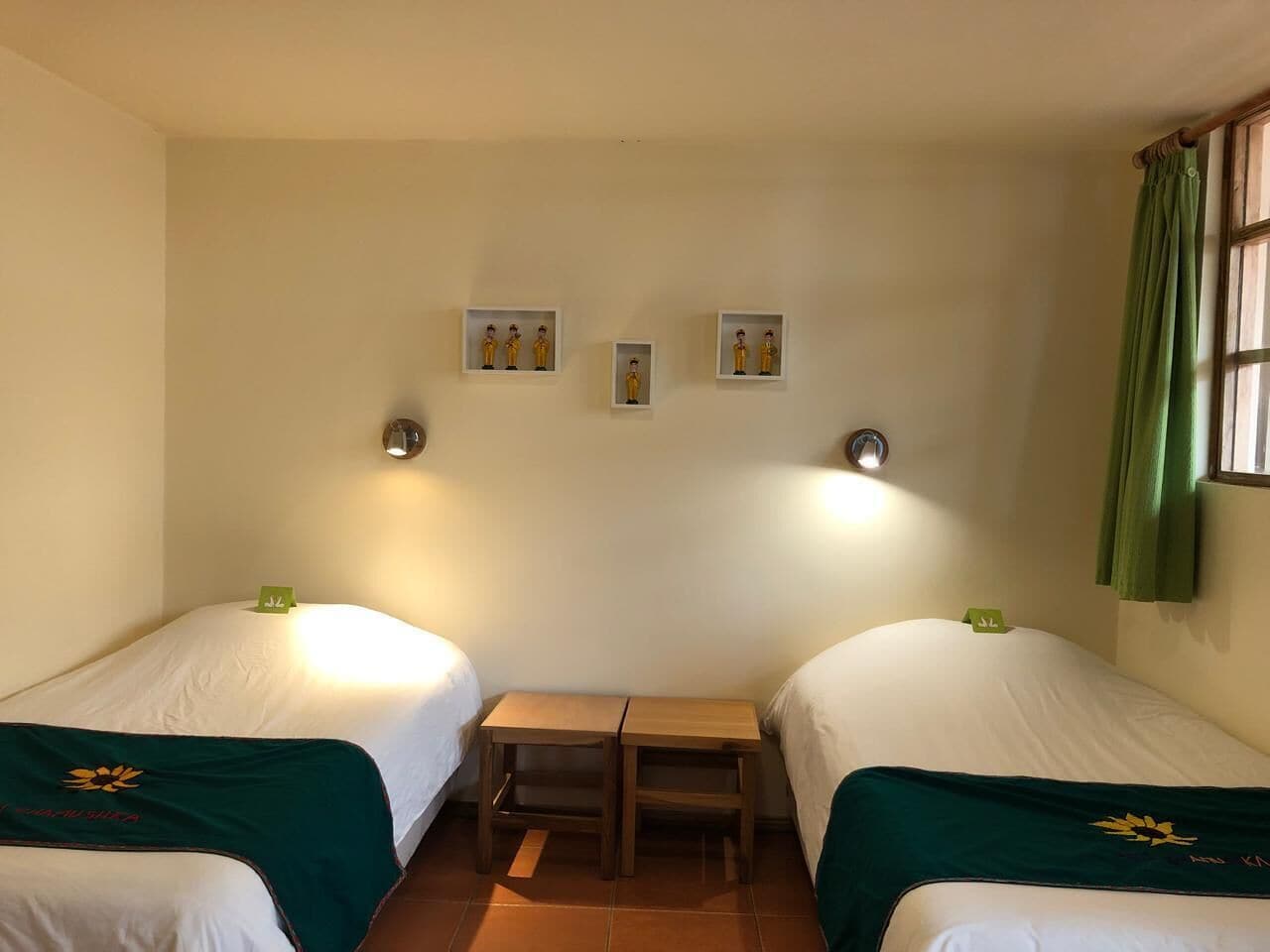 Ein Zimmer mit zwei Betten, einem kleinen Tisch und Wandleuchten.
