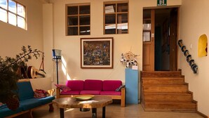 A cozy living room with a wooden floor, a red sofa, a coffee table, and a staircase leading to an upper level. - Inti Sisa (Guamote)