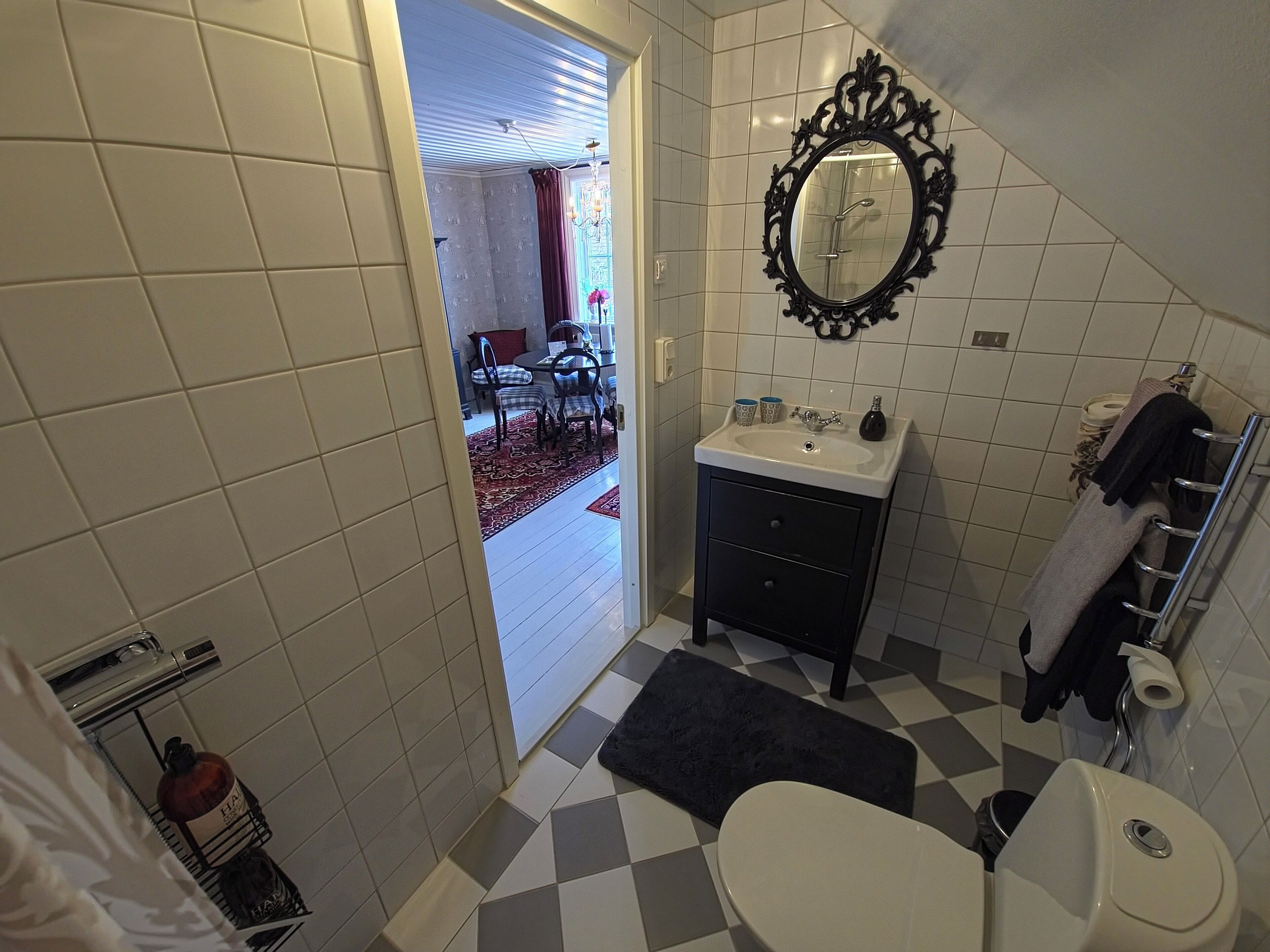 A bathroom with a toilet, sink, mirror, and towel rack.