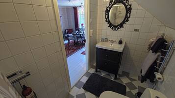 A bathroom with a toilet, sink, mirror, and towel rack.