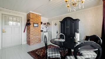 A dining area with a brick wall, a chandelier, and a black cabinet.