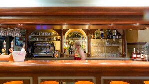 Una zona de bar con taburetes, una barra y un bartender.