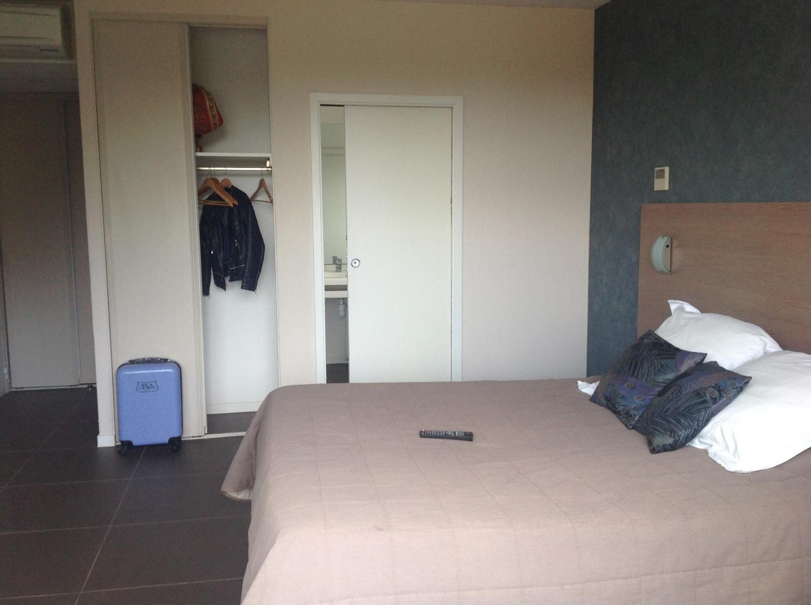 A hotel room with a bed, a wardrobe, and a suitcase.