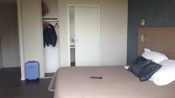A hotel room with a bed, a wardrobe, and a suitcase.